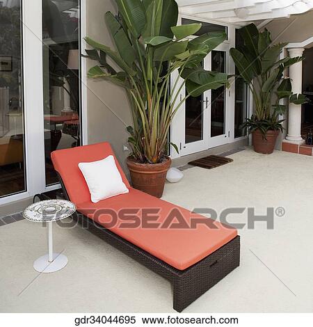 Stock Photography - Lounge chair and house plants on the porch of a house. Fotosearch