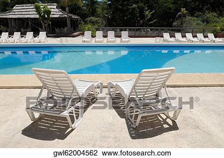 Stock Image - Lounge chairs at the poolside. Fotosearch