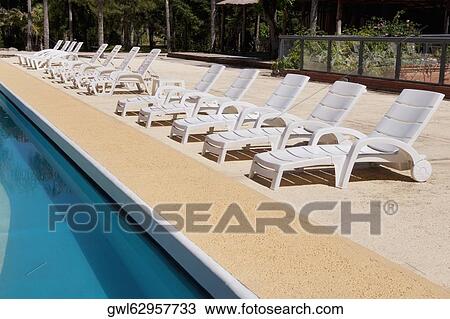 Stock Image - Lounge chairs at the poolside. Fotosearch