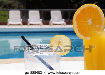 Lounge chairs with juices on table at the poolside View Large Photo Image Picture - Lounge chairs with juices on table at the poolside. Fotosearch