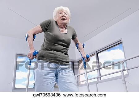 Low angle view of a woman using crutch View Large Photo Image Stock Photograph - Low angle view of a woman using crutch. Fotosearch
