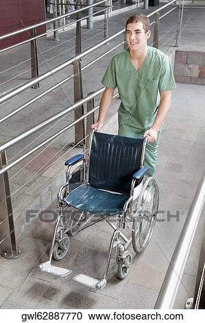 Male nurse carrying a wheelchair View Large Photo Image Stock Image - Male nurse carrying a wheelchair. Fotosearch