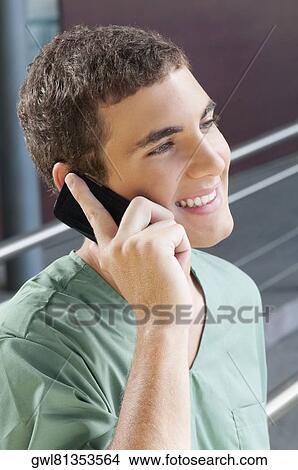 Picture - Male nurse talking on a mobile phone and smiling. Fotosearch
