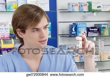 Male pharmacist holding a medicine bottle View Large Photo Image Picture - Male pharmacist holding a medicine bottle. Fotosearch