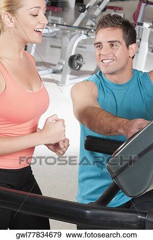 Stock Photo - Man assisting a woman on a treadmill. Fotosearch