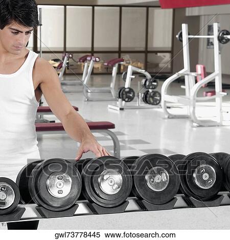 Man choosing dumbbells in a gym View Large Photo Image Stock Photography - Man choosing dumbbells in a gym. Fotosearch