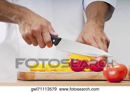 Man cutting a yellow bell pepper and tomatoes View Large Photo Image Stock Photo - Man cutting a yellow bell pepper and tomatoes. Fotosearch