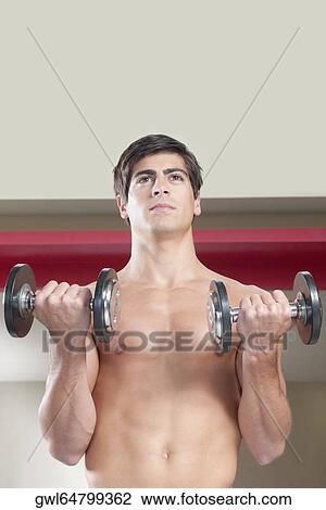 Man exercising with dumbbells in a gym View Large Photo Image Stock Image - Man exercising with dumbbells in a gym. Fotosearch