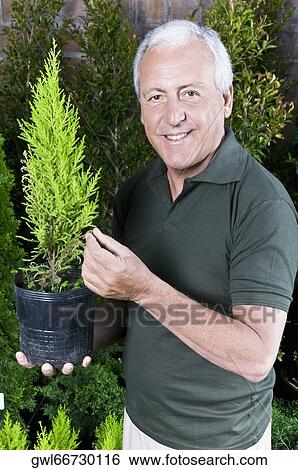 Man holding a potted plant View Large Photo Image Stock Photograph - Man holding a potted plant. Fotosearch