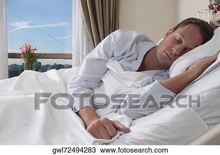Man lying in a hospital bed View Large Photo Image Stock Image - Man lying in a hospital bed. Fotosearch