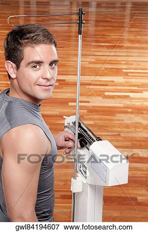 Stock Photo - Man measuring his weight on a weighing scale. Fotosearch