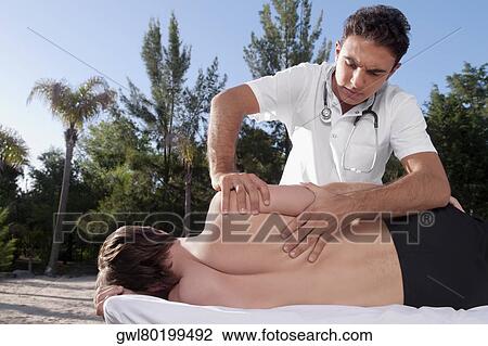 Stock Image - Man receiving a back massage from a massage therapist. Fotosearch