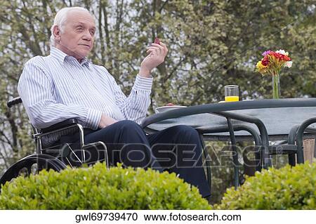 Man sitting in wheelchair in a garden View Large Photo Image Stock Image - Man sitting in wheelchair in a garden. Fotosearch