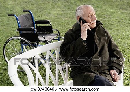 Man sitting on a chair and talking on a mobile phone View Large Photo Image Stock Photography - Man sitting on a chair and talking on a mobile phone. Fotosearch