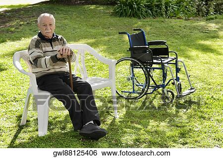 Stock Photograph - Man sitting on a chair in a park. Fotosearch