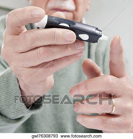 Stock Image - Man testing his blood sugar level. Fotosearch