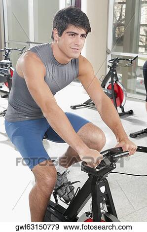 Man working out on an exercise bike in a gym View Large Photo Image Stock Photo - Man working out on an exercise bike in a gym. Fotosearch