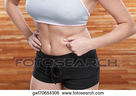 Mid section view of a woman pinching her waist View Large Photo Image Stock Photograph - Mid section view of a woman pinching her waist. Fotosearch