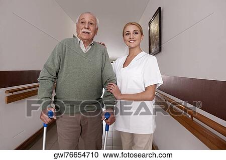 Nurse assisting a man to walk View Large Photo Image Stock Image - Nurse assisting a man to walk. Fotosearch