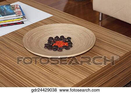 Pebbles in a wooden plate with magazines on a table View Large Photo Image Stock Photo - Pebbles in a wooden plate with magazines on a table. Fotosearch