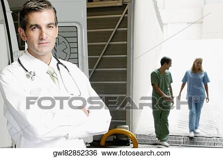 Portrait of a doctor with nurses in the background View Large Photo Image Stock Photograph - Portrait of a doctor with nurses in the background. Fotosearch