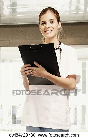 Portrait of a female doctor holding a clipboard and smiling View Large Photo Image Stock Image - Portrait of a female doctor holding a clipboard and smiling. Fotosearch