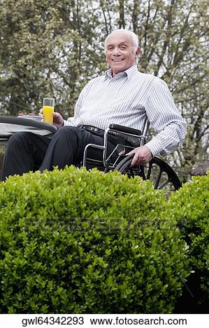 Portrait of a man sitting in a wheelchair and holding a glass of juice View Large Photo Image Stock Image - Portrait of a man sitting in a wheelchair and holding a glass of juice. Fotosearch
