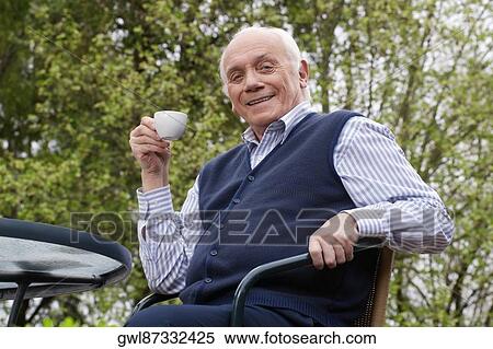 Stock Photography - Portrait of a man sitting on a chair and drinking tea. Fotosearch