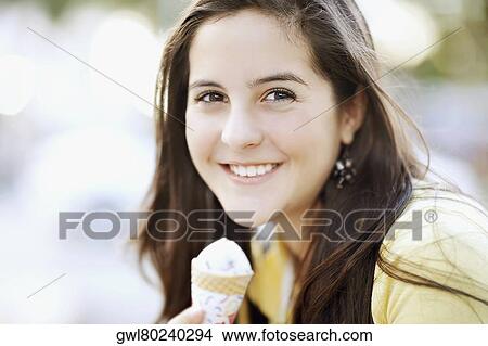 Picture - Portrait of a teenage girl eating an ice cream. Fotosearch