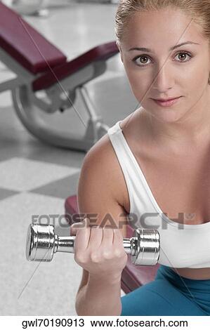 Portrait of a woman exercising with a dumbbell View Large Photo Image Stock Image - Portrait of a woman exercising with a dumbbell. Fotosearch