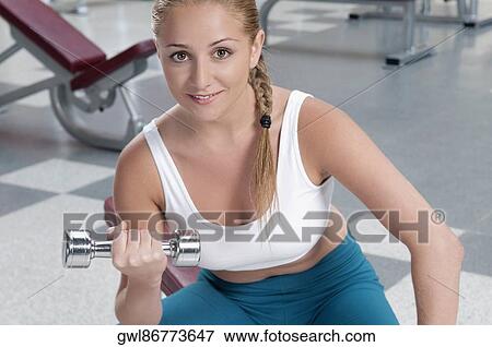 Portrait of a woman exercising with a dumbbell View Large Photo Image Stock Photo - Portrait of a woman exercising with a dumbbell. Fotosearch