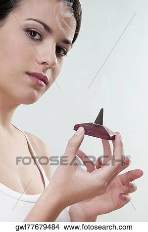 Portrait of a woman holding a burning incense cone View Large Photo Image Picture - Portrait of a woman holding a burning incense cone. Fotosearch