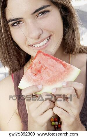 Stock Image - Portrait of a woman holding a slice of watermelon. Fotosearch