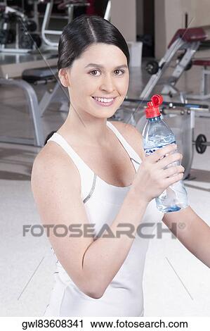 Portrait of a woman holding a water bottle in a gym View Large Photo Image Stock Image - Portrait of a woman holding a water bottle in a gym. Fotosearch