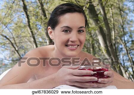 Portrait of a woman lying on a massage table holding a bowl of rose petals View Large Photo Image Stock Photo - Portrait of a woman lying on a massage table holding a bowl of rose petals. Fotosearch