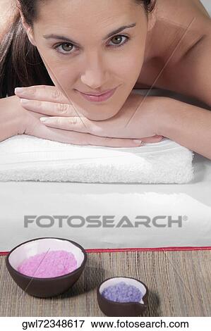 Stock Photo - Portrait of a woman lying on a massage table with bath salt. Fotosearch