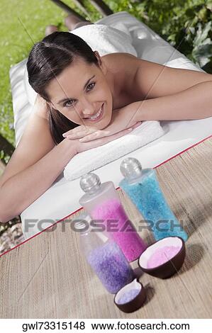 Portrait of a woman lying on a massage table with bath salt View Large Photo Image Stock Photo - Portrait of a woman lying on a massage table with bath salt. Fotosearch