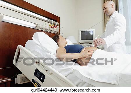 Pregnant woman going through an ultrasound scan View Large Photo Image Stock Photo - Pregnant woman going through an ultrasound scan. Fotosearch