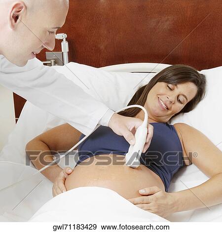 Pregnant woman going through an ultrasound scan View Large Photo Image Stock Photo - Pregnant woman going through an ultrasound scan. Fotosearch