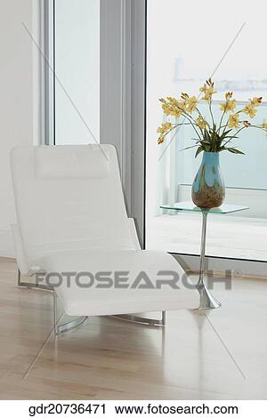 Stock Image - Reclining chair with a flower vase in a room. Fotosearch