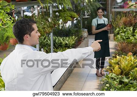 Scientist giving instructions to a woman in a greenhouse View Large Photo Image Stock Image - Scientist giving instructions to a woman in a greenhouse. Fotosearch