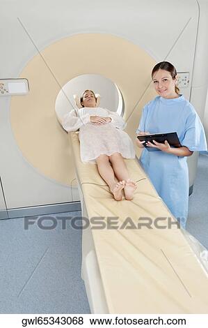 Surgeon checking medical report with a patient undergoing an MRI scan View Large Photo Image Stock Photo - Surgeon checking medical report with a patient undergoing an MRI scan. Fotosearch