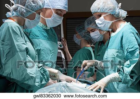 Stock Image - Surgeons performing a surgery in an operating room. Fotosearch