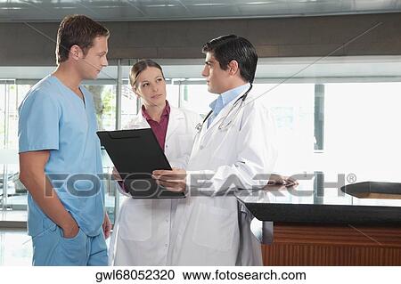 Three doctors discussing a medical report View Large Photo Image Stock Image - Three doctors discussing a medical report. Fotosearch