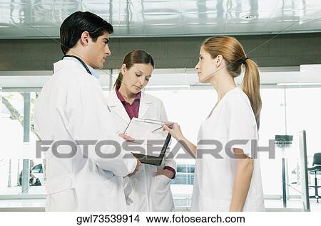 Three doctors discussing a report View Large Photo Image Picture - Three doctors discussing a report. Fotosearch