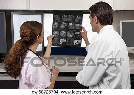 Two doctors examining MRI report View Large Photo Image Picture - Two doctors examining MRI report. Fotosearch