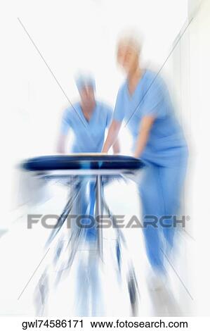 Two doctors pushing a gurney in a hospital corridor View Large Photo Image Stock Image - Two doctors pushing a gurney in a hospital corridor. Fotosearch