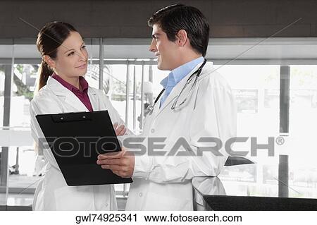 Two doctors talking in a hospital View Large Photo Image Stock Image - Two doctors talking in a hospital. Fotosearch