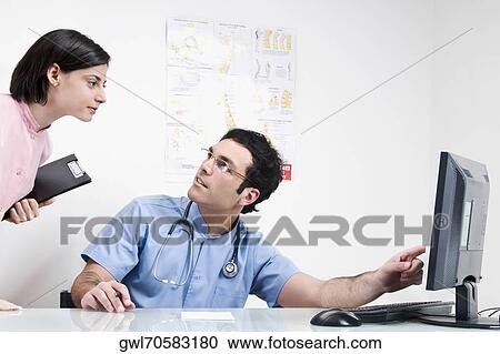 Stock Image - Two doctors working on a computer. Fotosearch