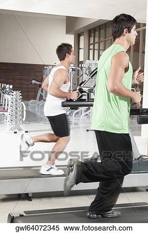 Two men running on treadmills View Large Photo Image Stock Photography - Two men running on treadmills. Fotosearch